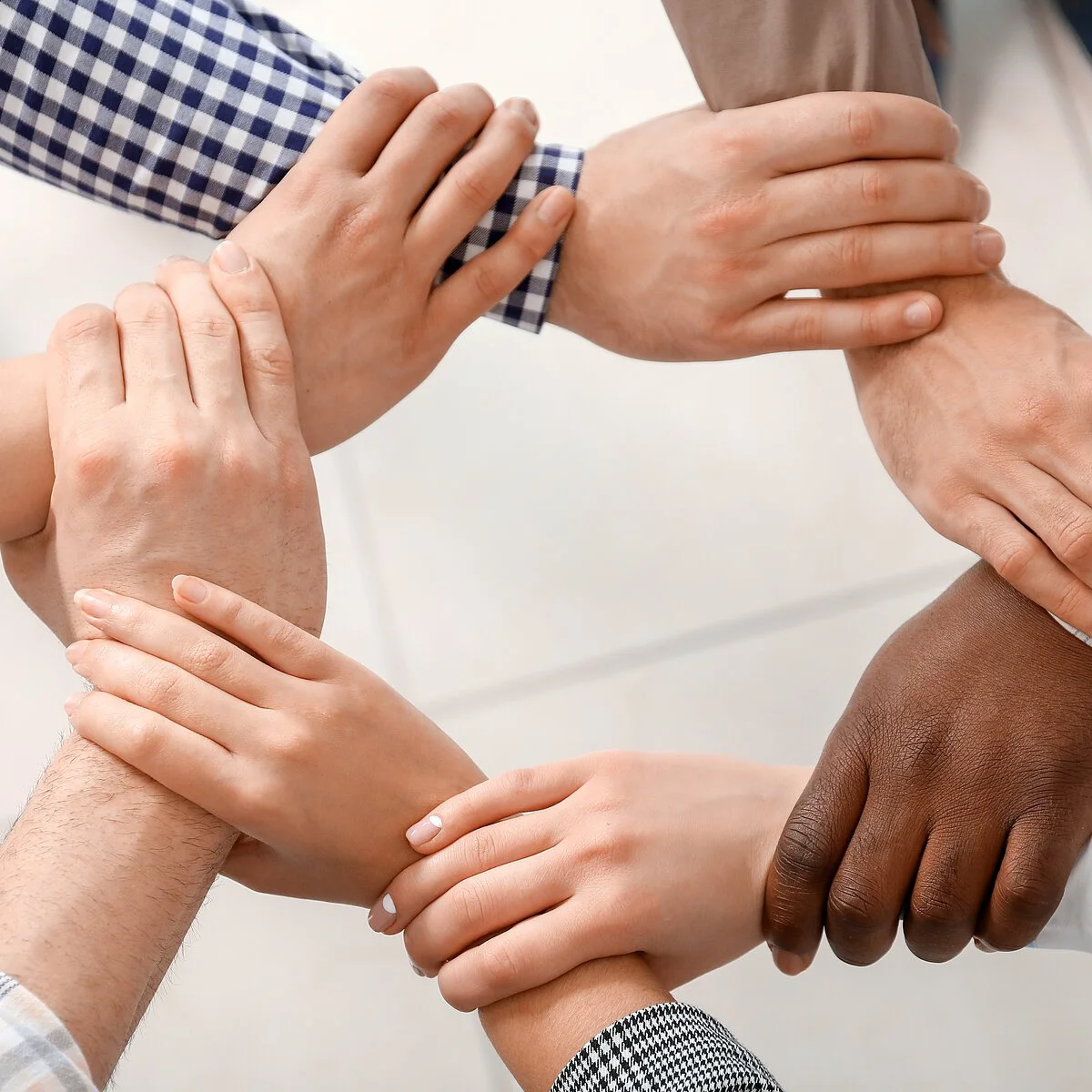 Group of people holding hands together indoors, top view. Unity concept Group of people holding hands together indoors, top view. Unity concept